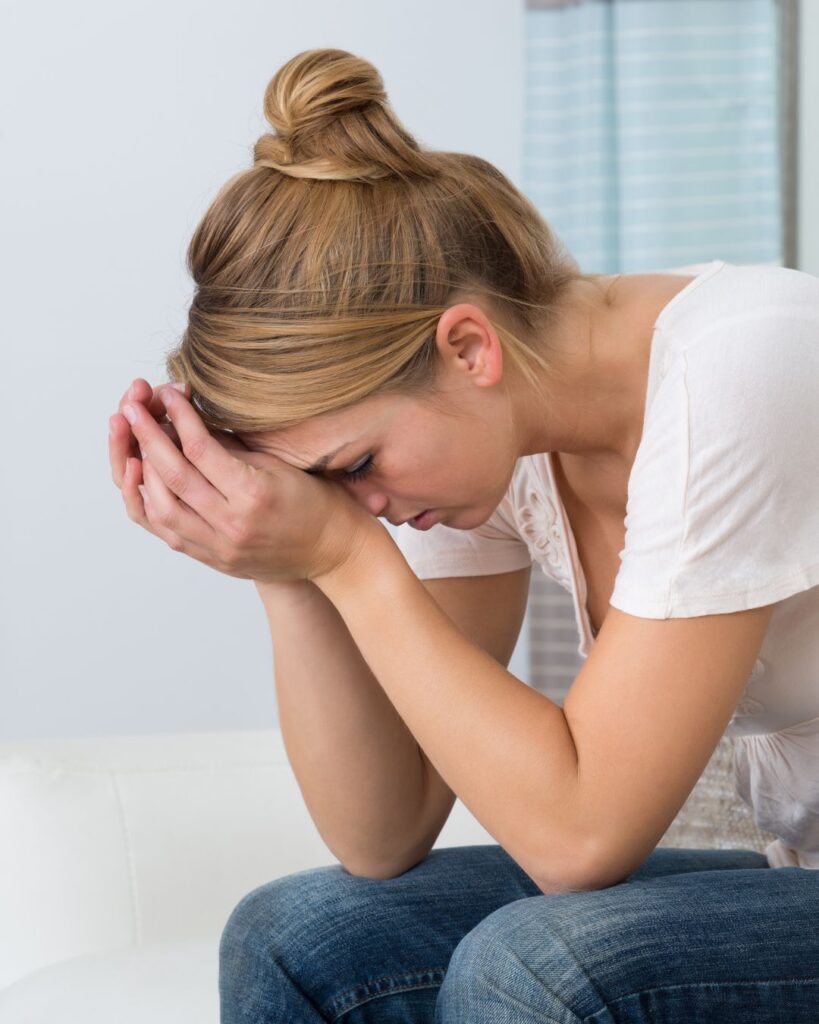 Exhausted woman resting her head in her hands, symbolizing the deep exhaustion common in peri menopause