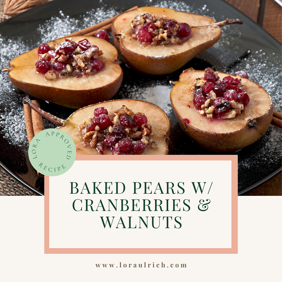 Baked pear halves filled with chopped walnuts and cranberries, garnished with cinnamon sticks on a dark plate.