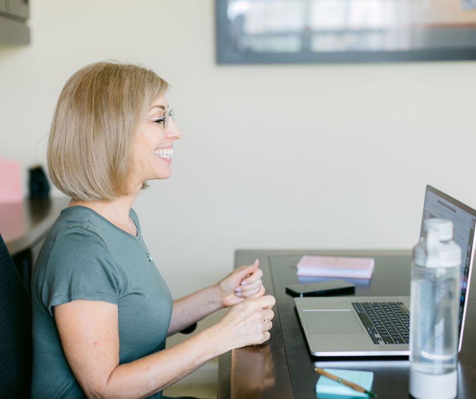 Midlife health coach smiling during a virtual call, offering warm, personalized support for women navigating perimenopause.