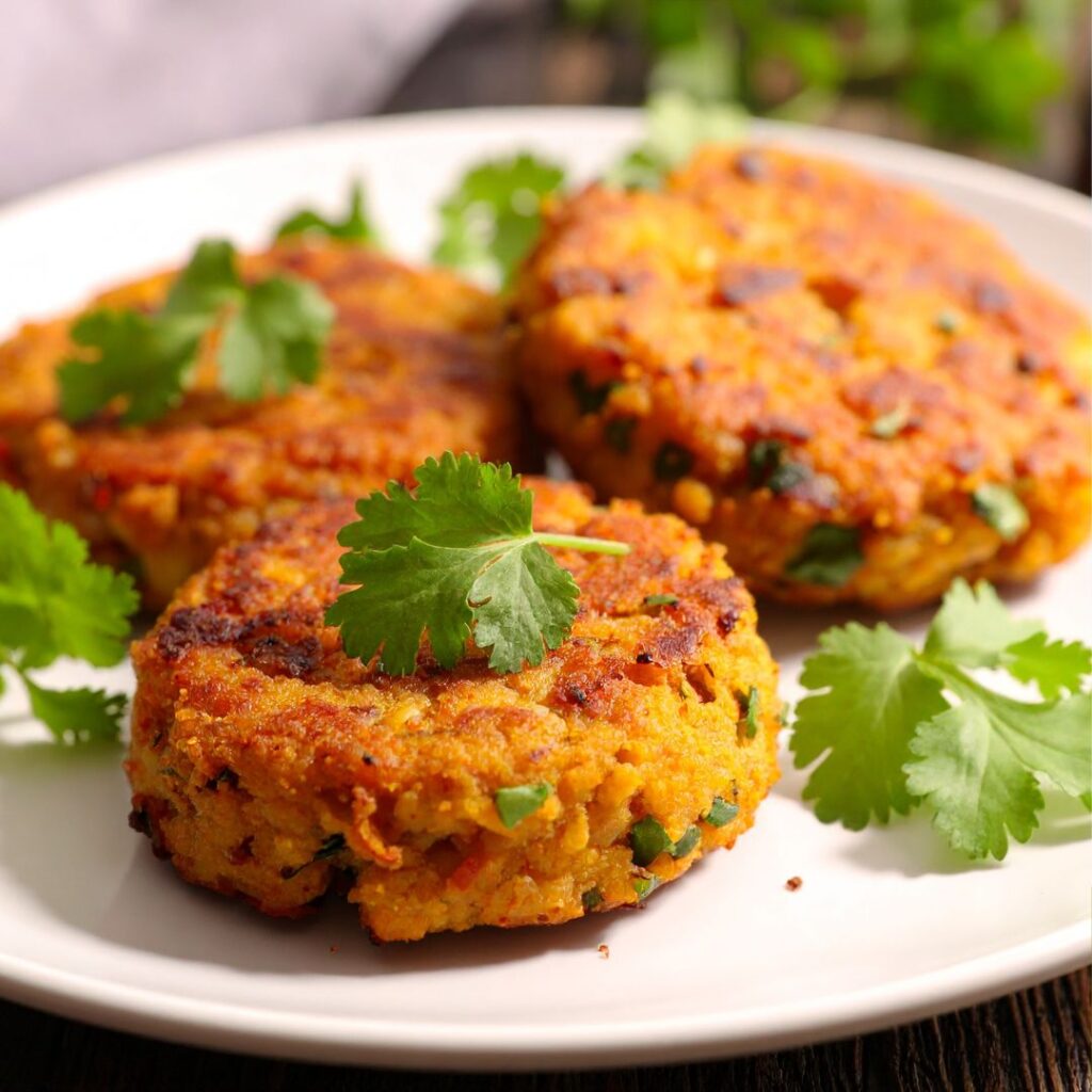 Golden-brown lentil patties arranged on a plate, served with fresh herbs.