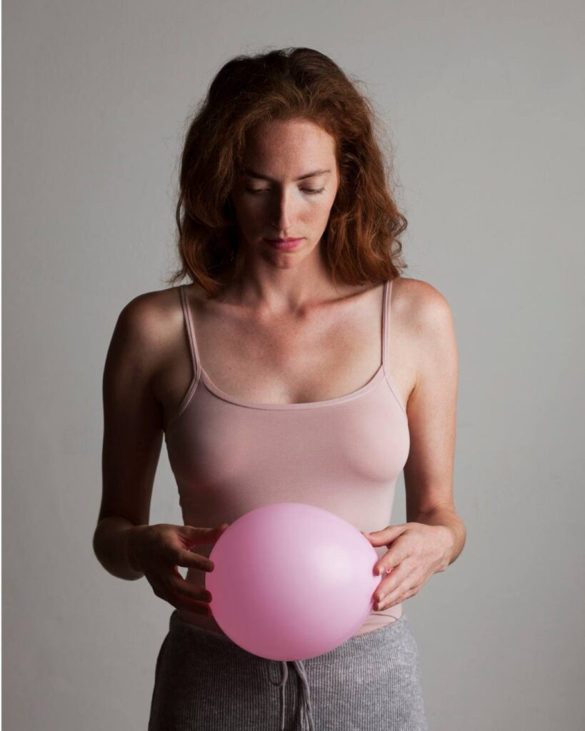 Woman gently holding a balloon over her belly, symbolizing perimenopause bloating.