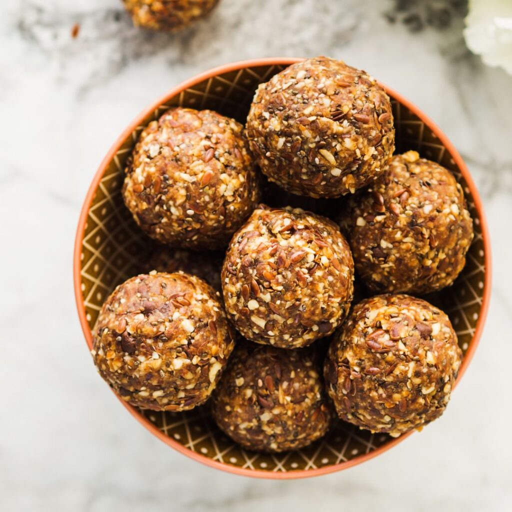 A small bowl filled with soft, fudgy chocolate almond butter balls, chilled and ready to serve as a dairy-free holiday treat.