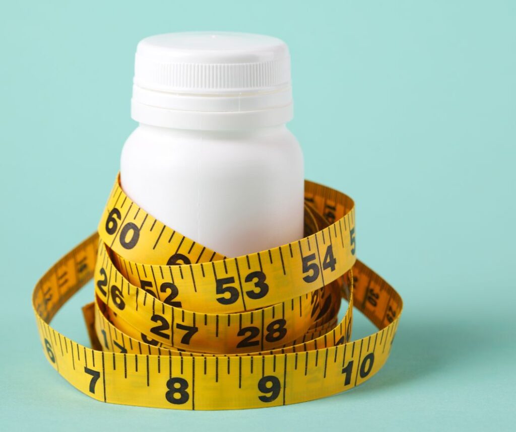 Menopause weight loss pills concept with supplement bottle and tape measure.