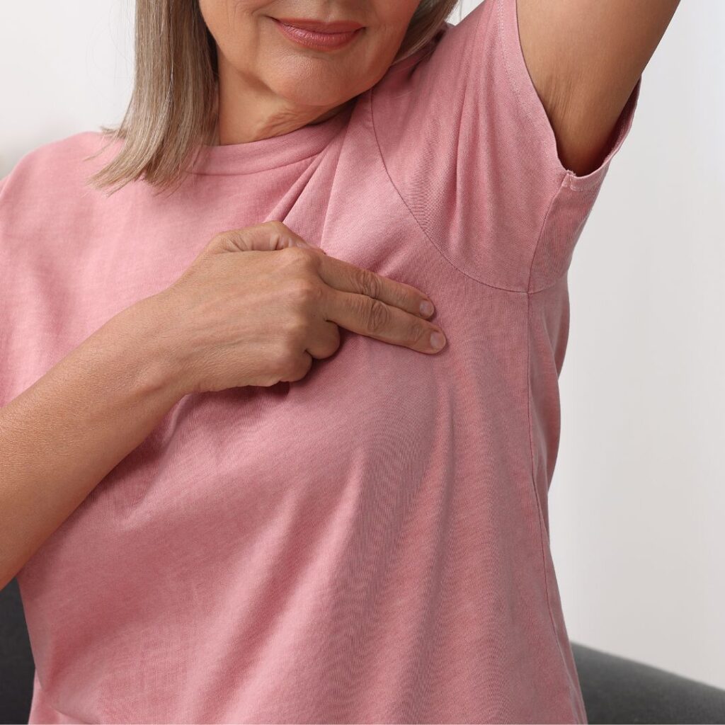 Woman pointing to her underarm area, illustrating a breast self-check related to postmenopausal nipple soreness and midlife breast awareness. 