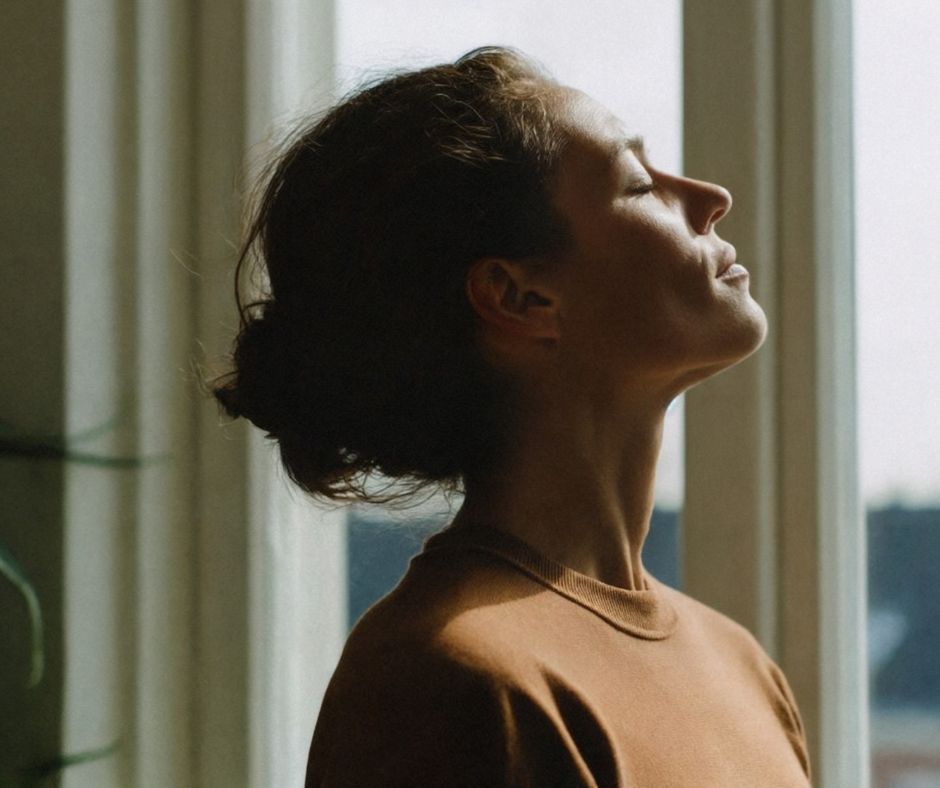 Midlife woman smiling outdoors in natural light, symbolizing confidence and wellness during perimenopause.