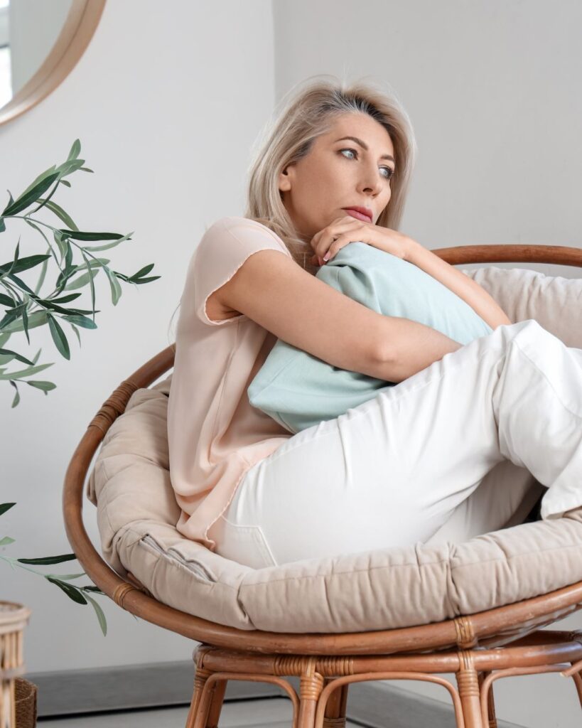 A midlife woman sitting quietly, looking thoughtful and wondering about perimenopause weird symptoms.