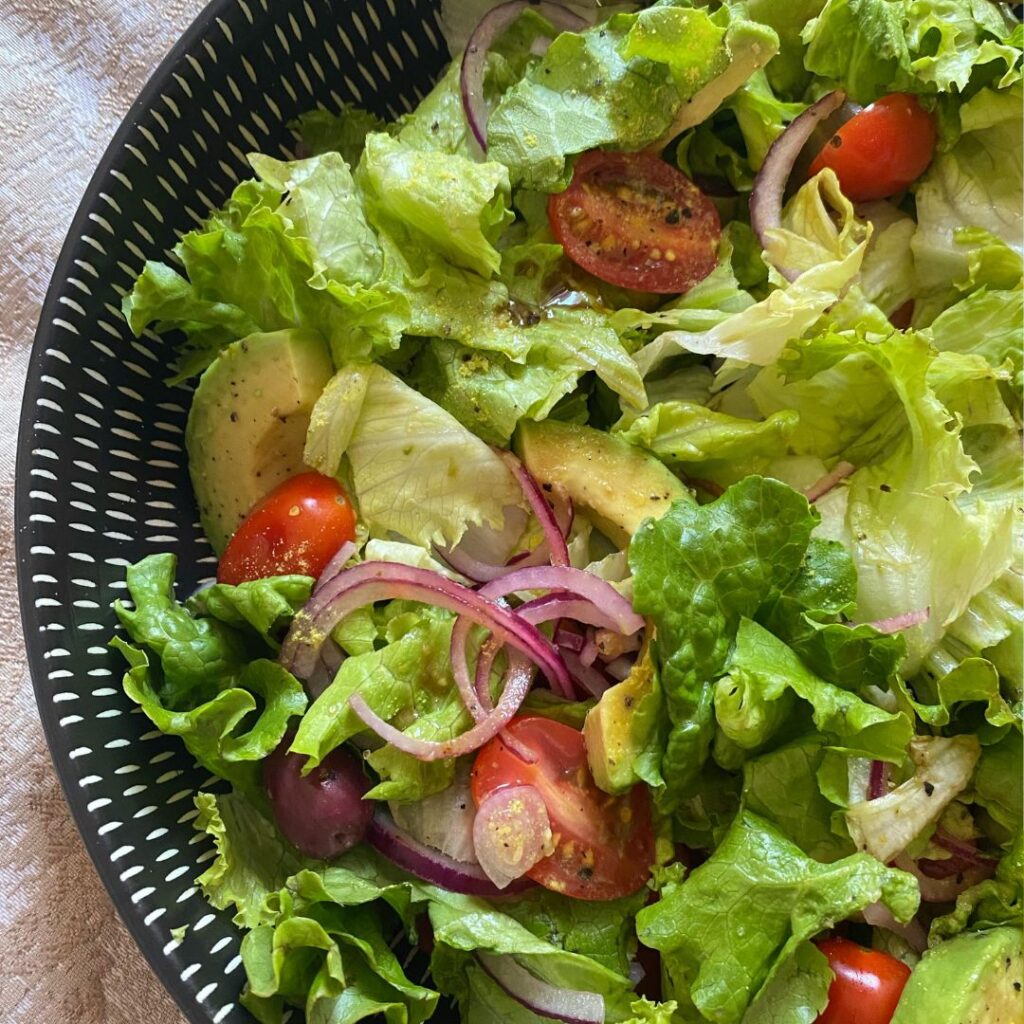 A fresh avocado and tomato salad, featuring crisp lettuce leaves, halved cherry tomatoes, and creamy avocado chunks.