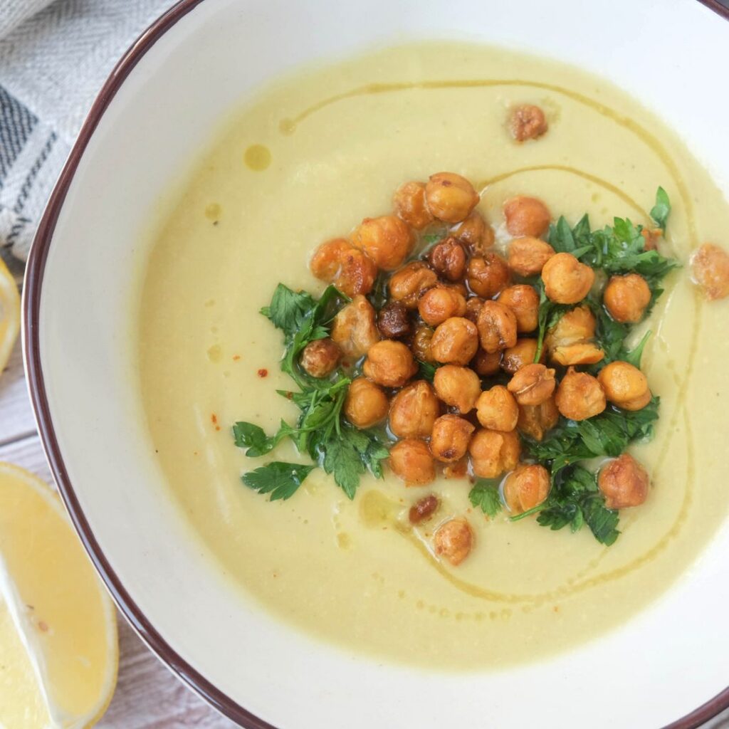 Creamy golden chickpea lemon soup topped with crispy chickpeas, fresh parsley, and a drizzle of olive oil in a white bowl.