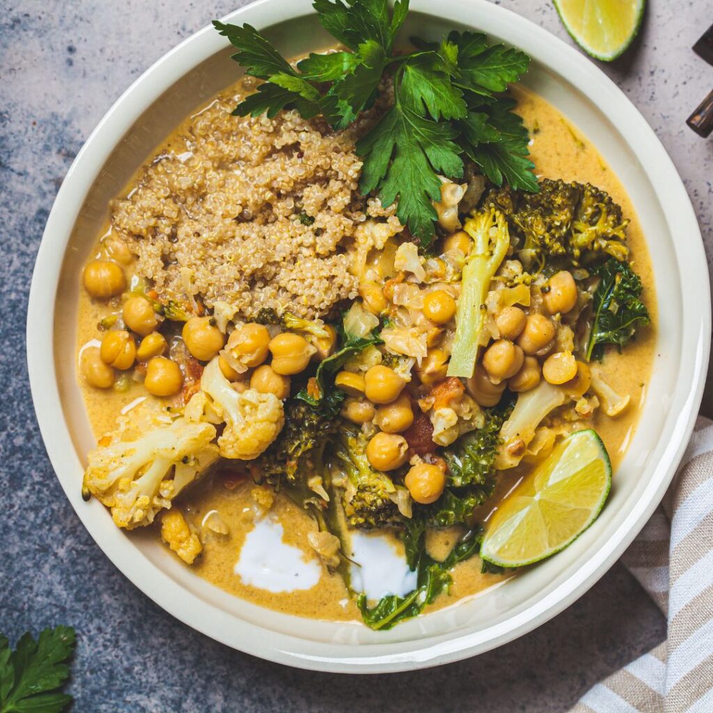 A nourishing bowl of cauliflower chickpea curry with quinoa, garnished with fresh herbs and lime, crafted as a hormone-friendly meal to support women in menopause.