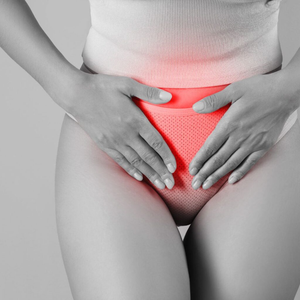 Midlife woman holding lower abdomen with red highlight indicating pelvic pain or discomfort, symbolizing perimenopause heavy bleeding.