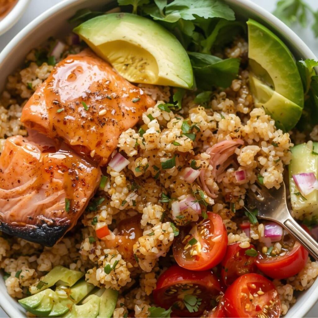 A vibrant salmon quinoa bowl with a seared, glazed salmon fillet, sliced avocado, cherry tomatoes, over a bed of fluffy quinoa for midlife hormone balance.