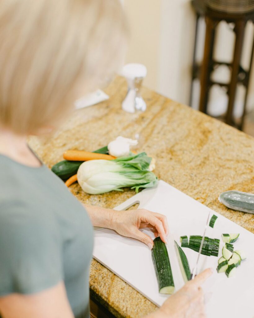 Menopause Health Coach Lora Ulrich preparing a fresh meal as part of her Menopause Metabolism Method. This holistic menopause solution focuses on nutrient-dense food to manage midlife weight gain.