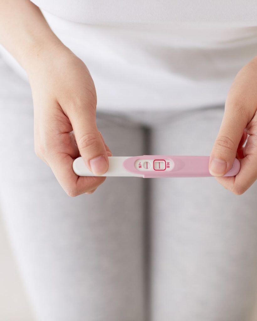 Close-up of a midlife woman holding a pregnancy test asking can you get pregnant during perimenopause.