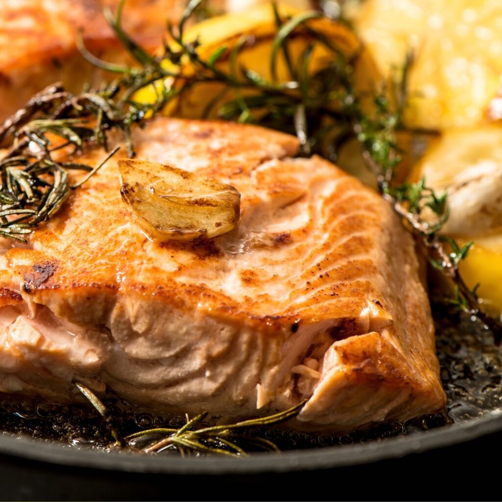 Close-up of lemon herb salmon baked with garlic, lemon slices and thyme on a sheet pan.
