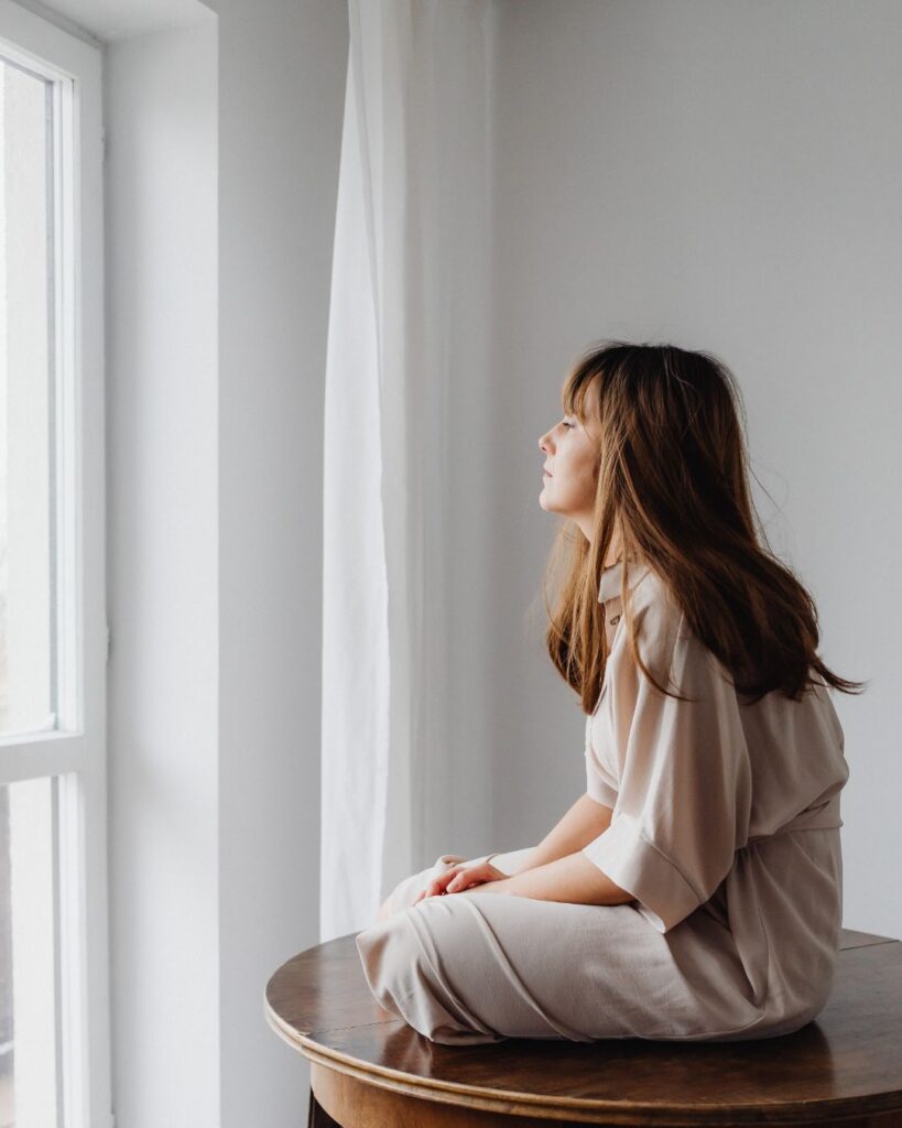 A calm woman in a peaceful indoor setting, illustrating the importance of mindful reflection and lifestyle support for managing menopause depression.