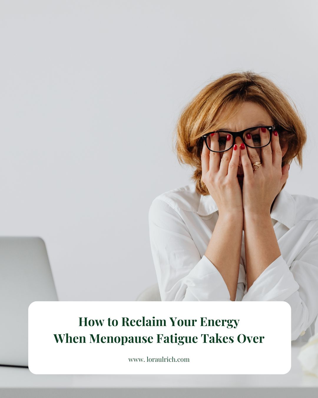 Midlife woman sitting at her desk with her head in her hands, illustrating the exhaustion and overwhelm of menopause fatigue.