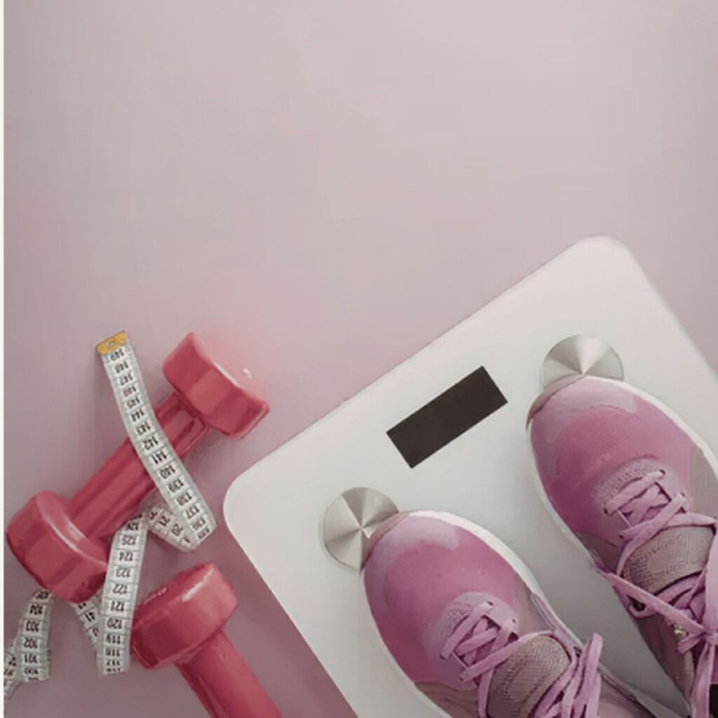 Fitness equipment including pink dumbbells and a scale, representing the physical and hormonal components of an effective menopause weight loss diet and metabolic reset.