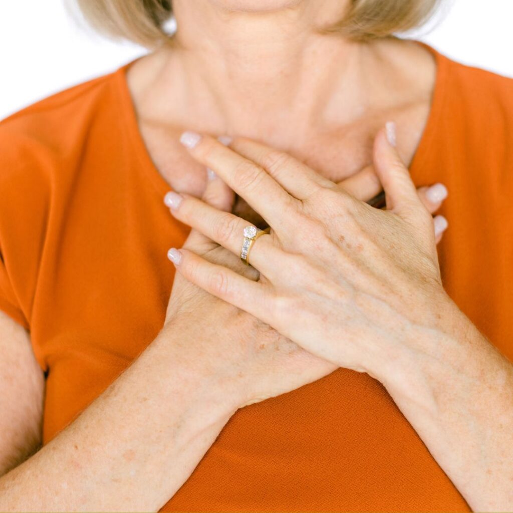 Health Coach Lora Ulrich demonstrating the physical sensation of chest pressure and burning often felt during the midlife transition. 