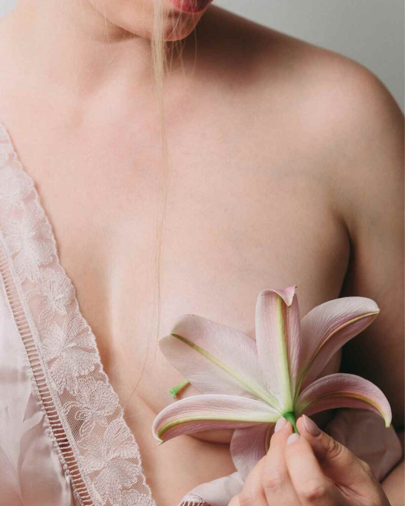 Pink lily resting near the chest area to represent postmenopause painful breasts and gentle breast tissue sensitivity.