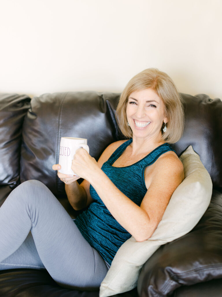 Relaxed and smiling midlife woman in athletic wear, enjoying a drink from a mug, illustrating a balanced approach to menopause symptom management.