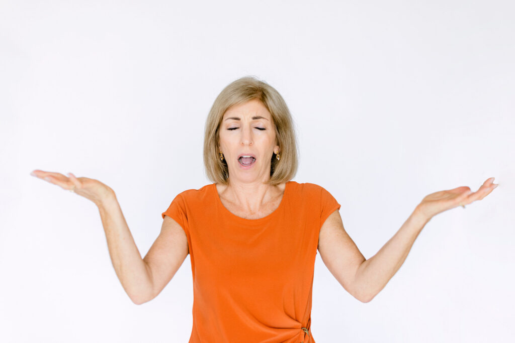 Woman experiencing postmenopausal memory loss and brain fog with hands raised in confusion.