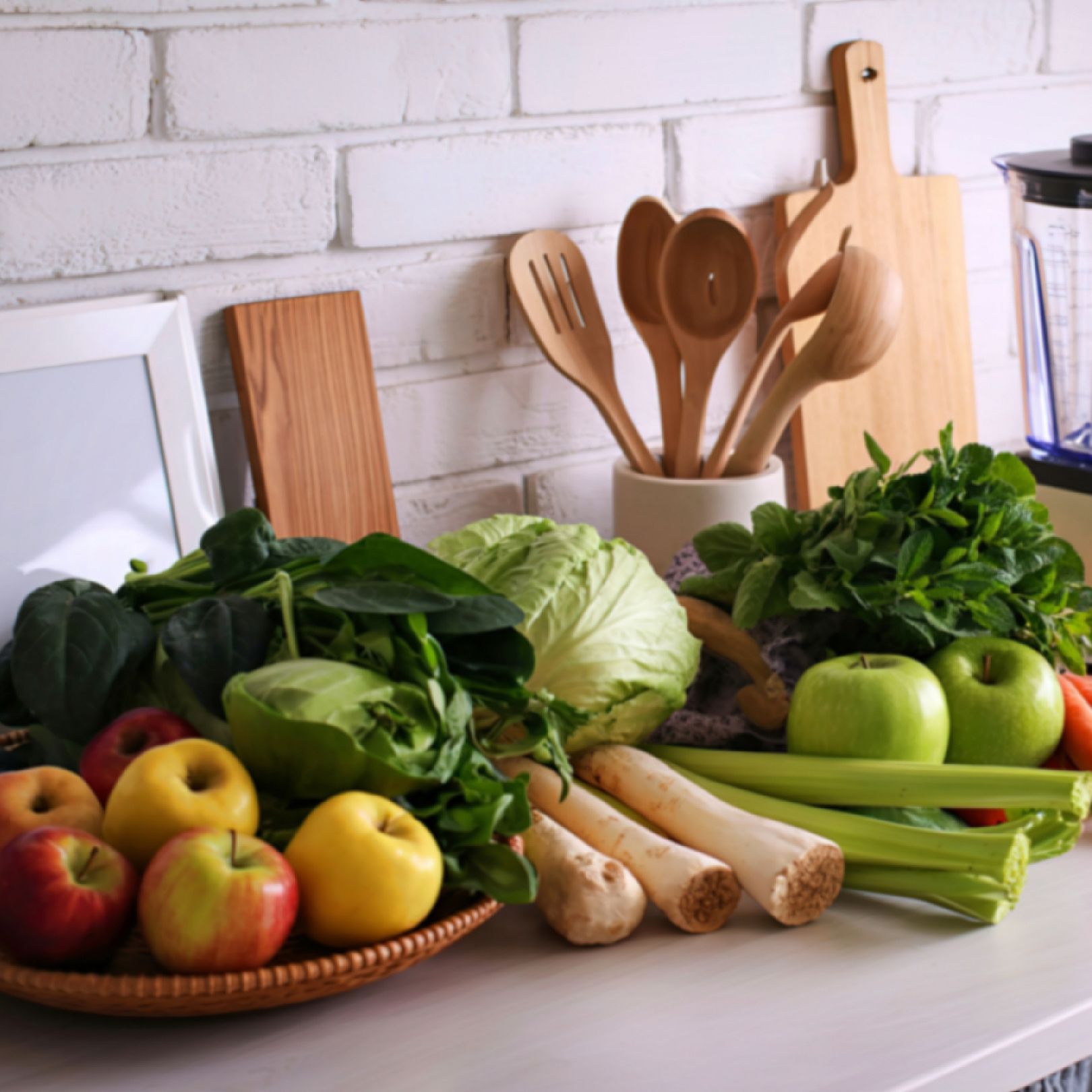 Fresh leafy greens, apples, celery, and whole vegetables displayed on a kitchen counter for hormone balancing and blood sugar support.