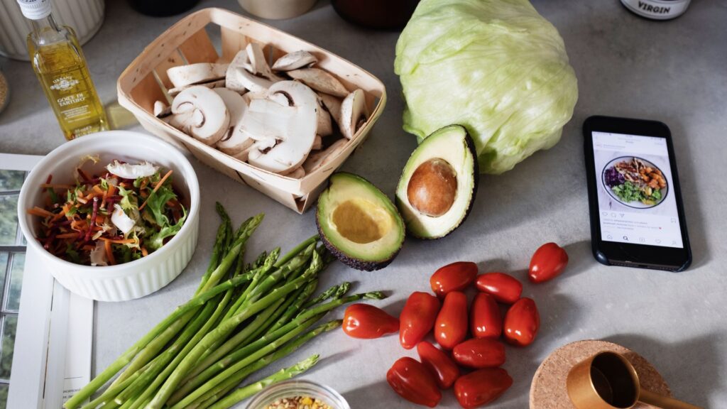 Fresh high-fiber vegetables, healthy fats including halved avocados, asparagus, cherry tomatoes, and sliced mushrooms spread on a counter for blood sugar balance.